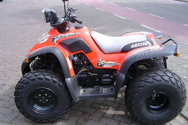 Orange und schwarzes ATV auf der Straße geparkt, zeigt sein sportliches Design und die robusten Reifen.