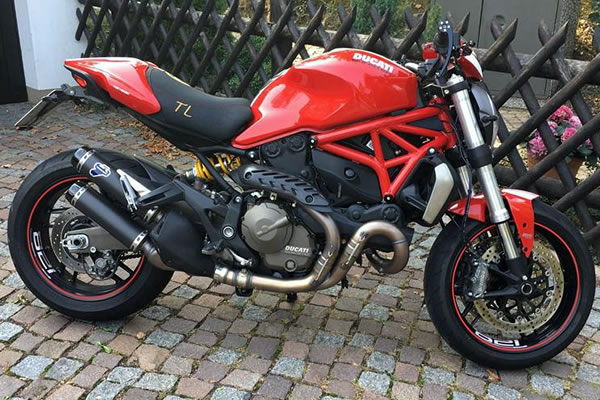 Rotes Ducati Motorrad auf einer Kopfsteinpflasteroberfläche geparkt.