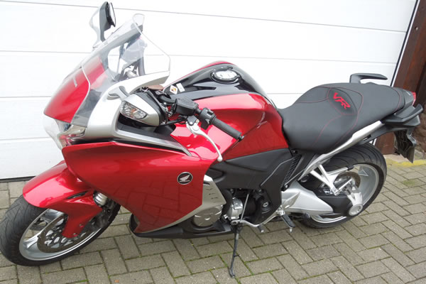 Rotes Honda VFR Motorrad auf einer gepflasterten Oberfläche geparkt.