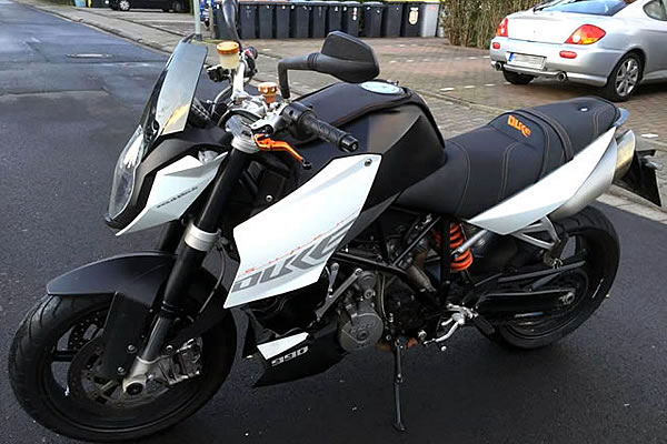 Schwarzes und orangefarbenes KTM Duke Motorrad auf einer gepflasterten Oberfläche geparkt.