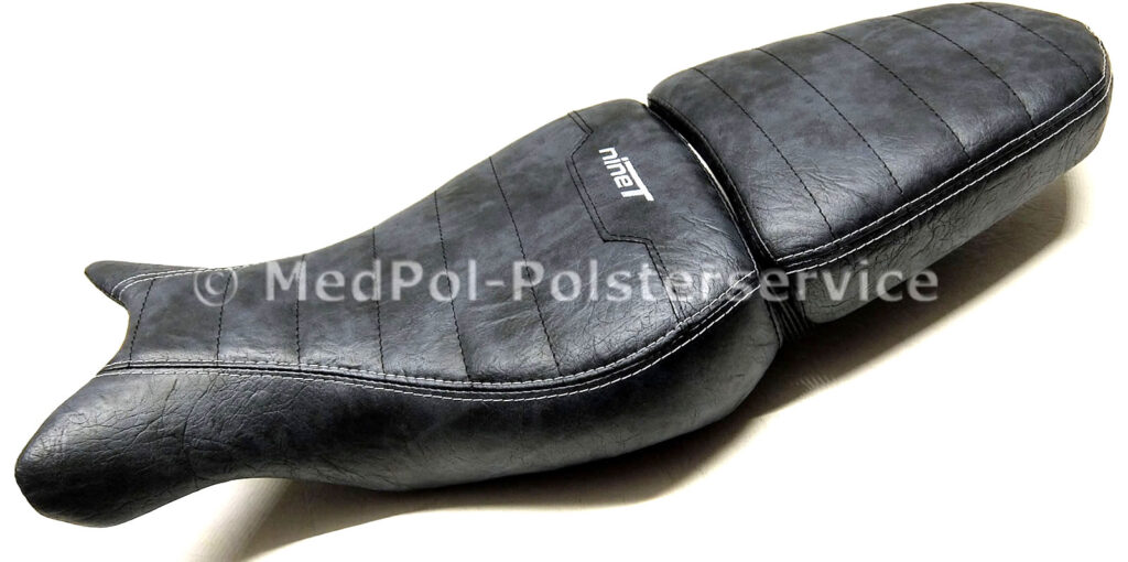 R nineT Fahrer- und Soziussitz komplett Neubezug in Used Look AC36, Quersteppung mit dunkelblauer Ziernaht, doppelte Ziernaht und Stickerei in Silber. Mit körperspezifischer Komfortpolsterung/Gel-Aktivmatte.