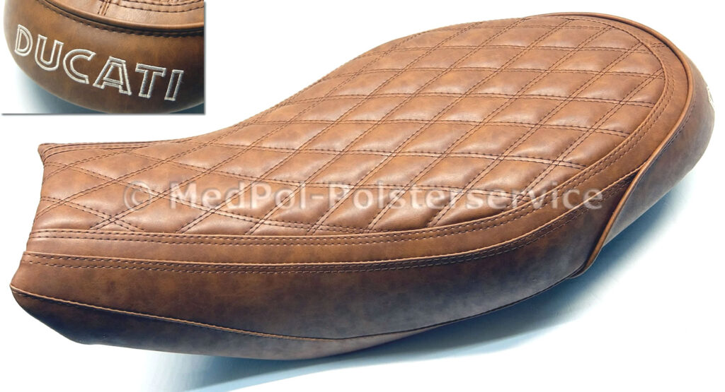 Scrambler Sitzbank komplett Neubezug in Harrison mit Komfortpolsterung/Gel-Aktivmatte, zusätzlicher Aufpolsterung um 1cm, Rautensteppung mit doppelter Ziernaht Glaichfarbig, Stickerei in Beige.