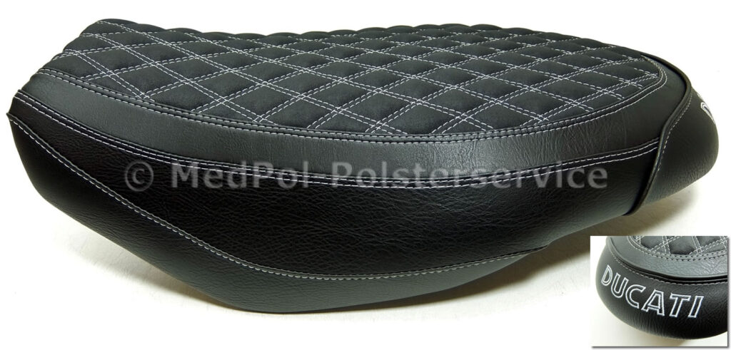 Scrambler An den Körper angepasste Sitzbank mit Komfort/Aktivmatte und einer zusätzlichen Erhöhung von 6cm mittig gearbeitet, den Neubezug aus Nubuck und Vintage Schwarz, Rautensteppung doppelt und mit einer Stickerei in Hellgrau gefertigt.